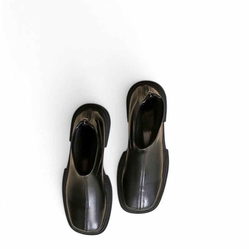 A pair of shiny black leather boots with square toes and back zippers, displayed from the top on a white background.