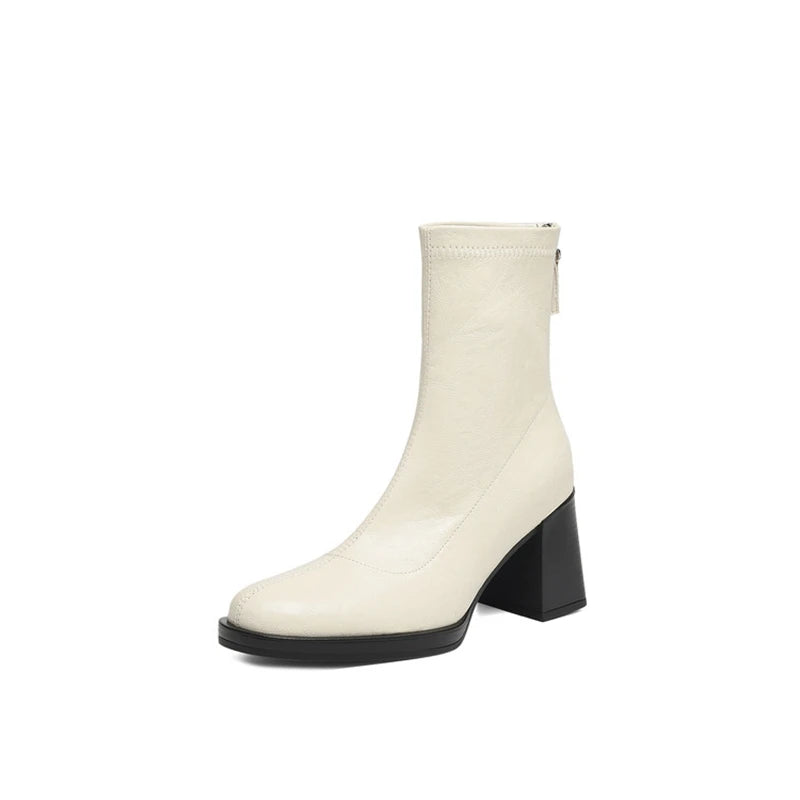 Sleek white leather boot featuring a mid block heel and clean silhouette