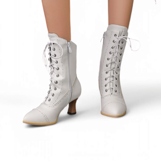 A front view of a woman wearing white mid-calf Victorian lace-up boots with pointed toes and kitten heels, standing on a white background.
