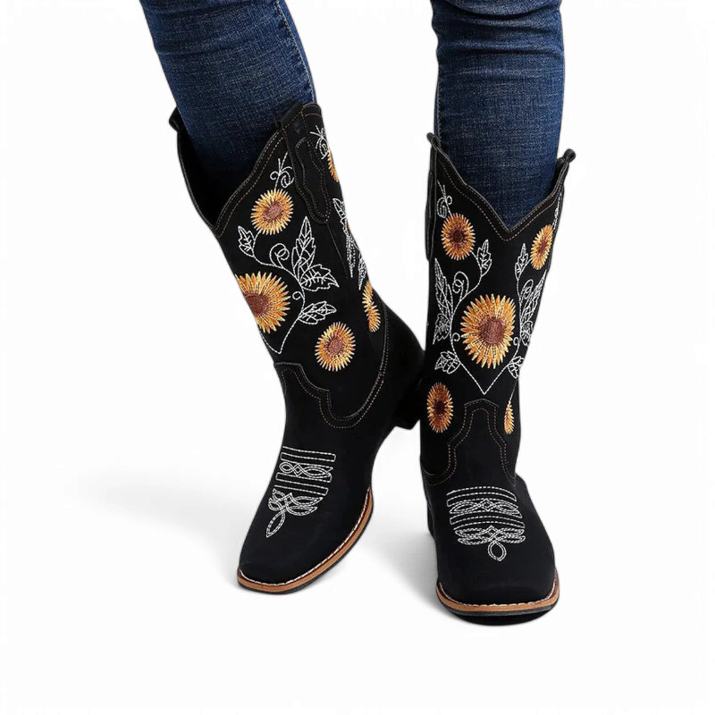 Front view of black sunflower-embroidered cowboy boots on feet, paired with dark denim.