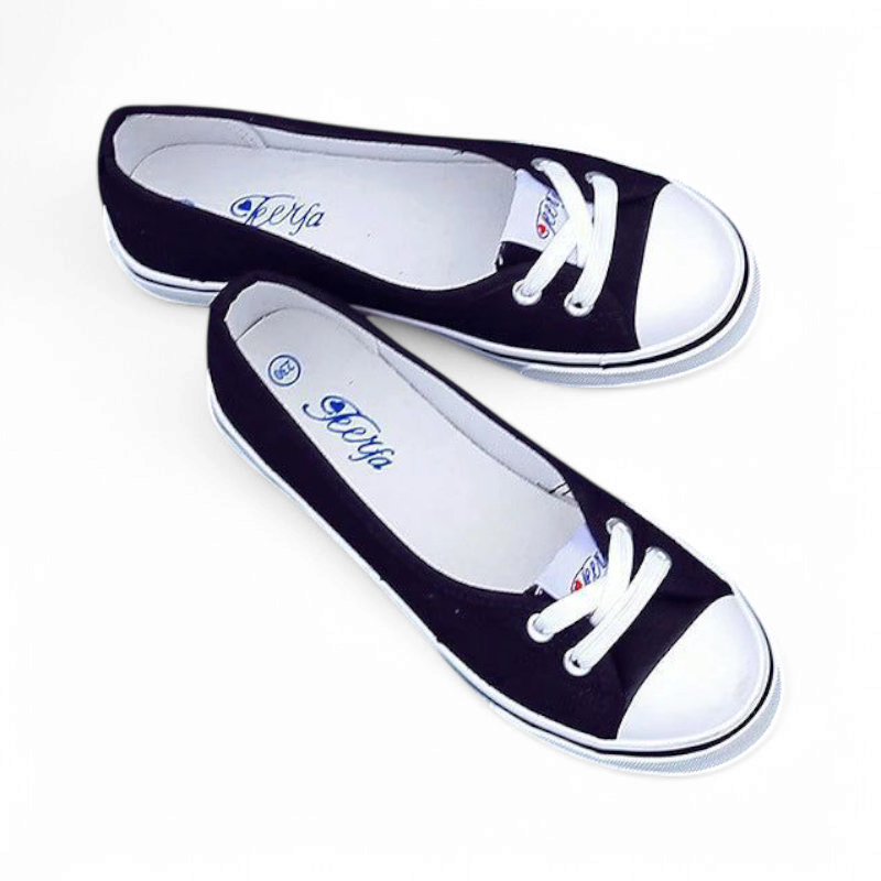 Angled top view of black canvas flat with crossed lace detail and white cap toe.