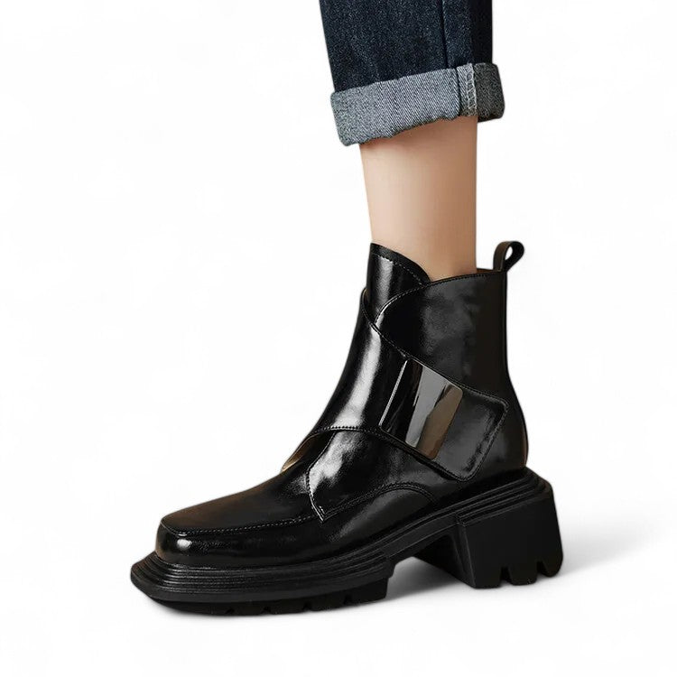 Glossy black ankle boot worn on foot with geometric design and thick heel