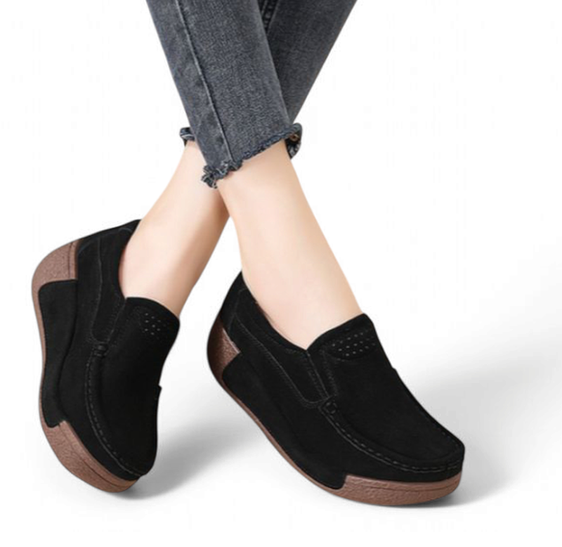 Woman wearing black suede platform loafers with brown wedge‑style outsole