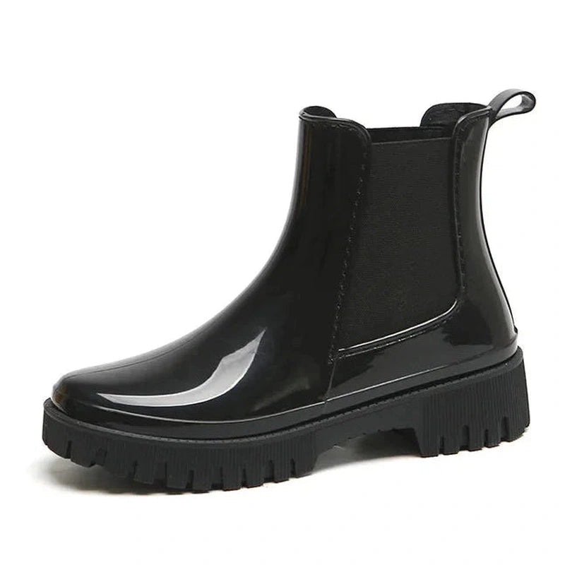 Glossy black Chelsea boot with round toe and chunky heel – side view.